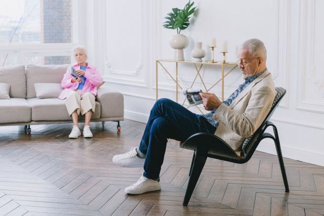Coffret cadeau offert a un couple de seniors Grands-parents ouvrant un coffret cadeau dans leur salon